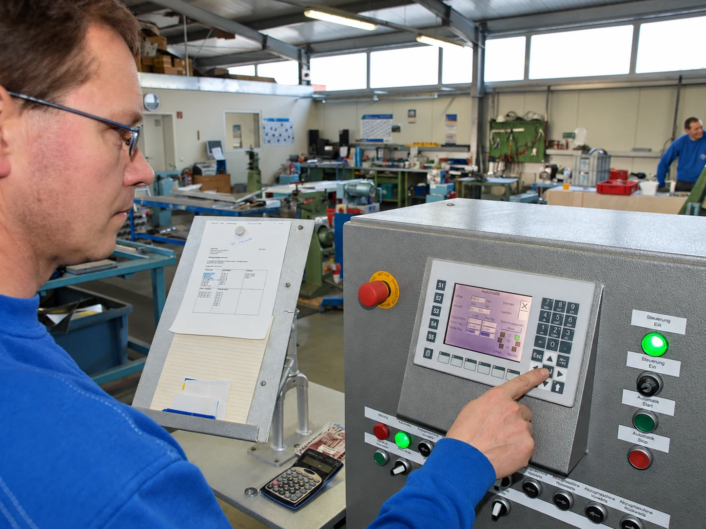 Mitarbeiter bedient die Steuerung einer Blechbearbeitungsmaschine in der MECO-TECH-Werkstatt.